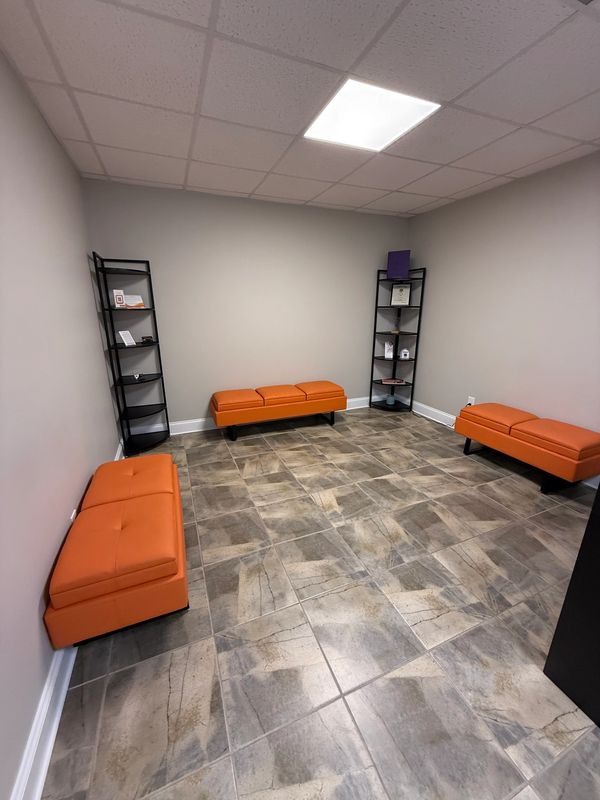 Modern waiting room with orange benches and shelves.