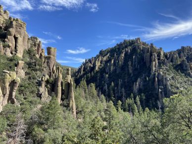 Rocky cliffs and green trees under a bright blue sky.