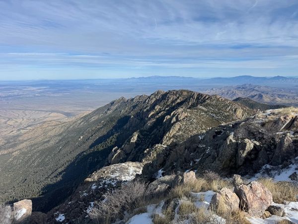 Mountain ridge with snow patches under a partly cloudy sky.