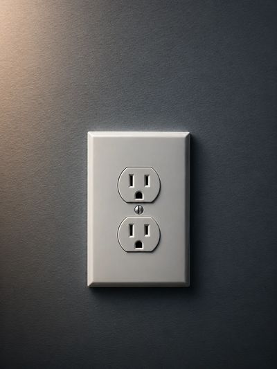 Close-up of a white electrical outlet on a dark wall.