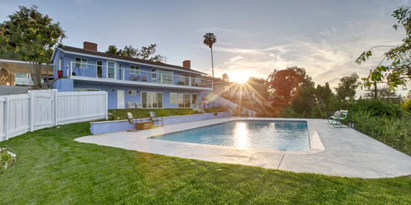 A spacious backyard with a swimming pool at sunset.