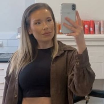 Young woman taking a mirror selfie indoors.