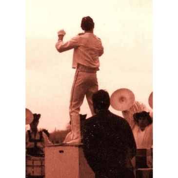 Person standing on a platform directing or conducting.