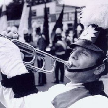 A marching band member plays the trumpet during a parade.