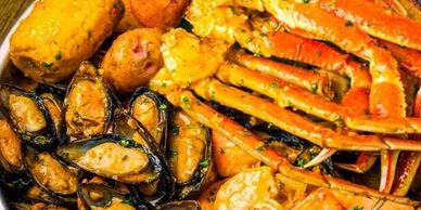 A seafood boil with crab legs, mussels, potatoes, and corn.