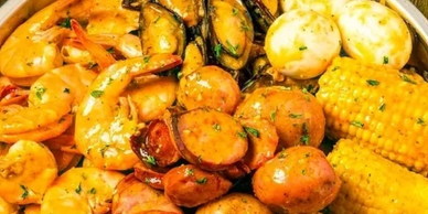 A colorful seafood boil with shrimp, sausage, mussels, corn, and boiled eggs.
