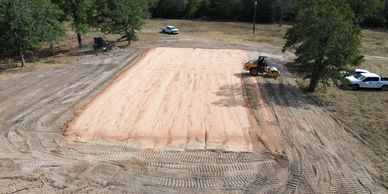 A leveled dirt area under construction with machinery and vehicles nearby.