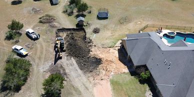 Excavation work being done near a house with a pool in the backyard.