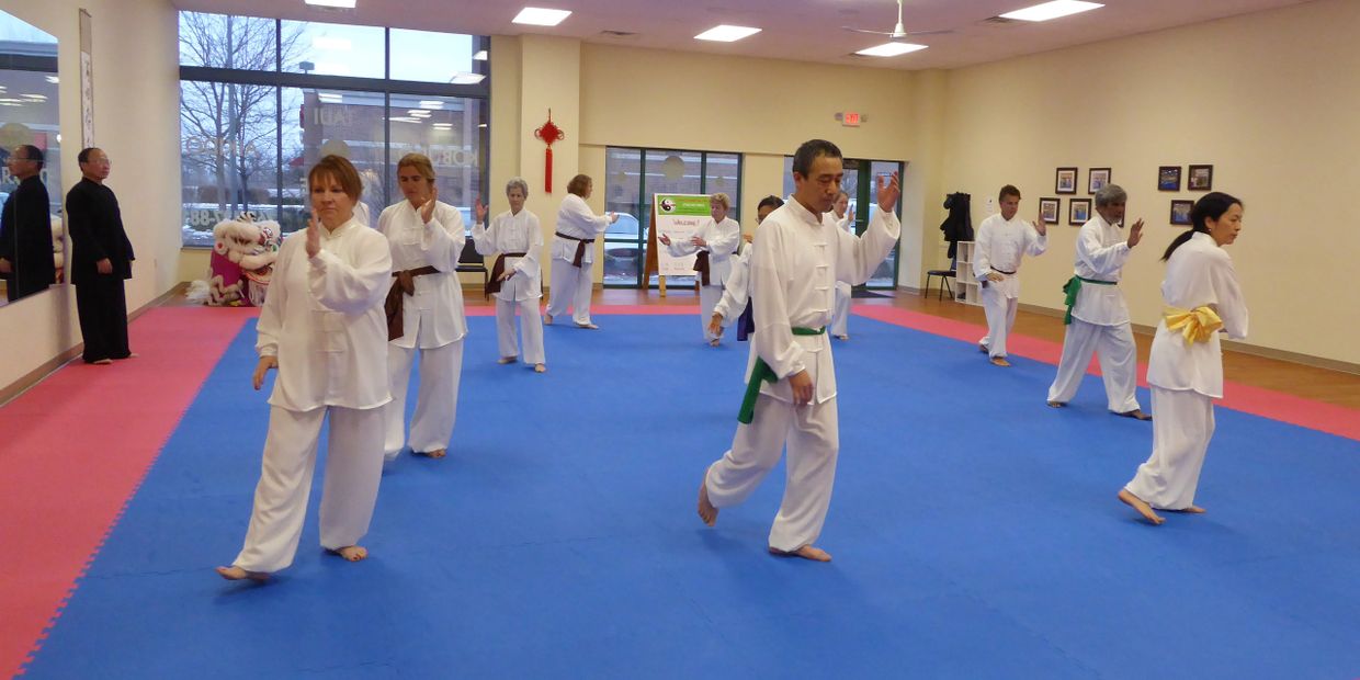 Students of all skill levels learn Yang Taiji (tai chi) at Master Ling's in Noblesville, IN.  Tai chi students in traditional uniforms practice Yang 24 forms taiji.  Red and blue training mat in Tai Chi school.