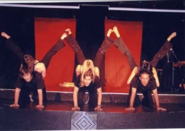 Three performers balancing on their hands and feet on stage.