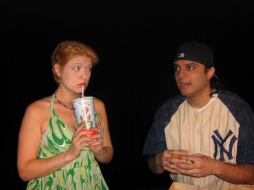 Two people having a conversation, one drinking from a cup.