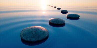 path of smooth stones in calm water at sunrise