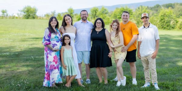 A family of eight people posing outdoors on grass in the community.