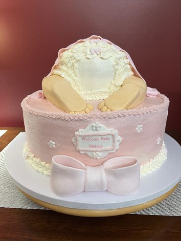 Pink baby shower cake with a baby bottom and feet design.
