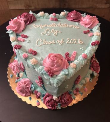 Heart-shaped congratulatory cake decorated with pink and blue flowers.