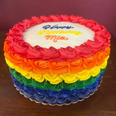 Colorful rainbow layered cake with birthday message.