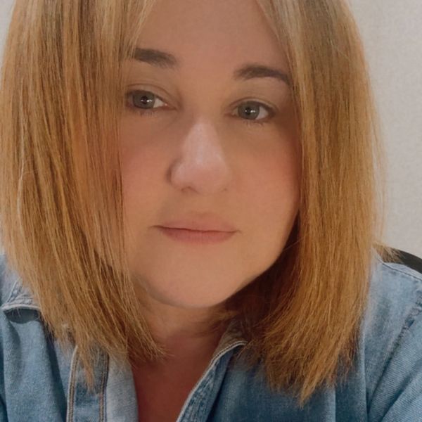 Close-up portrait of a woman with straight light brown hair and a denim jacket.