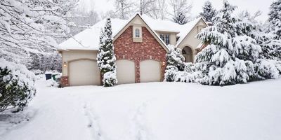 A beautiful house covered in fresh snow with snowy trees surrounding it.