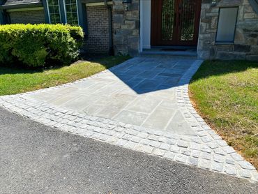 Stone walkway with cobblestone border leading to a front door.