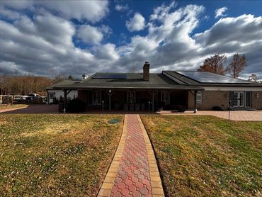 A single-story house with solar panels under a partly cloudy sky.