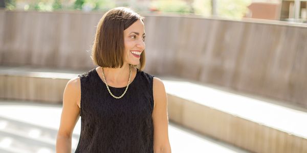 Smiling woman in a black sleeveless top outdoors.