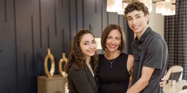 A happy mother with her teenage son and daughter posing indoors.