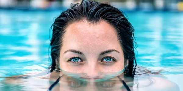 Person with striking blue eyes partially submerged in water.