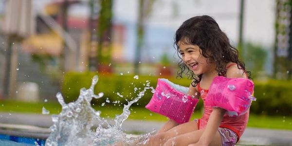 A joyful child playing and splashing water by the poolside.