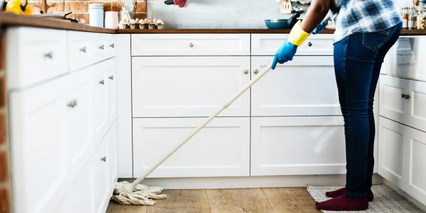 Person mopping the kitchen floor wearing gloves and socks.