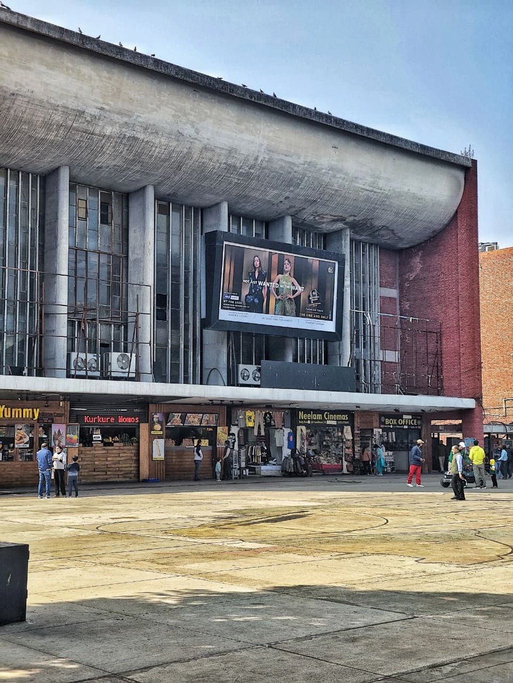 Exterior of a cinema with people outside and shops.