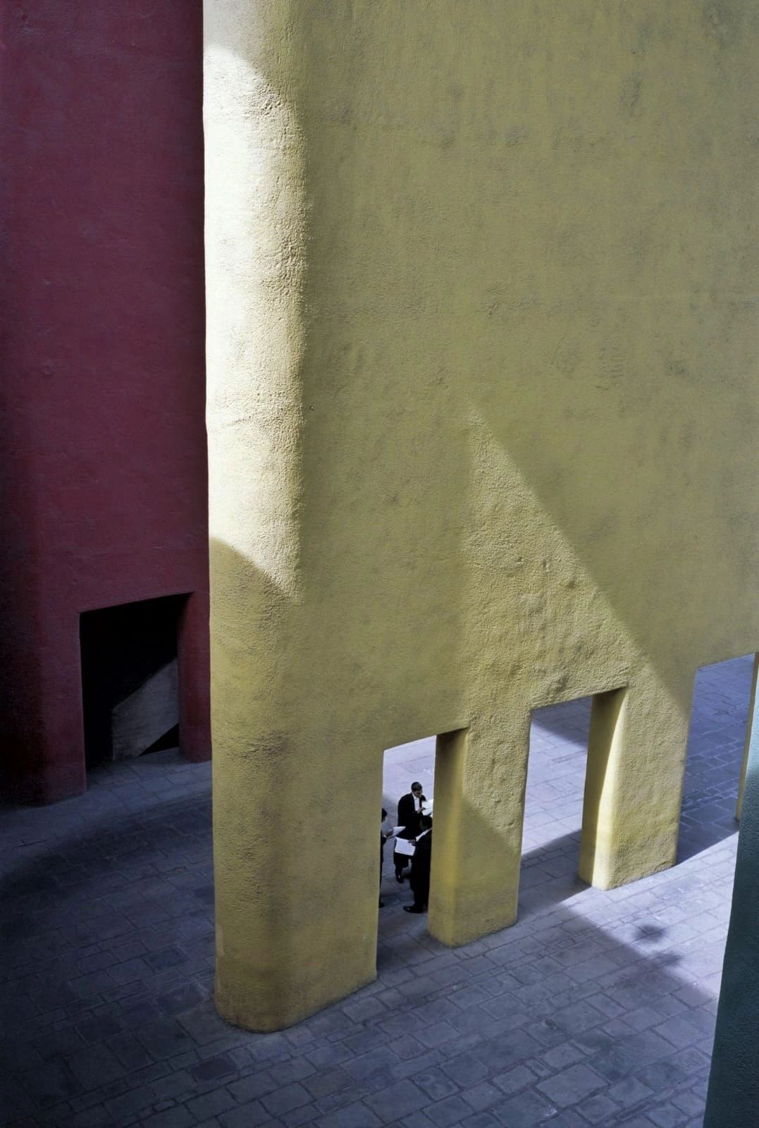 People interacting under large, colorful concrete arches.