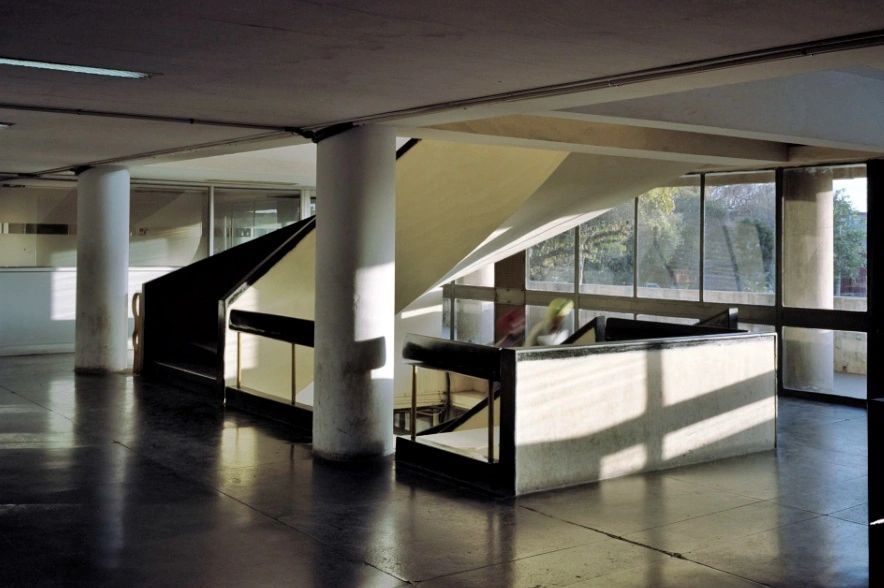 Modern, sunlit staircase inside a building with large windows.