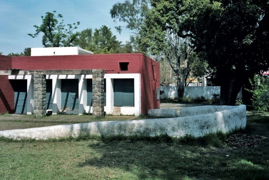 Small building with stone pillars and red walls.