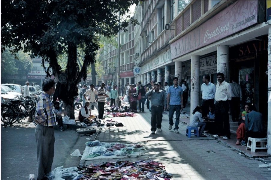 Busy open-air market street with people and stalls.