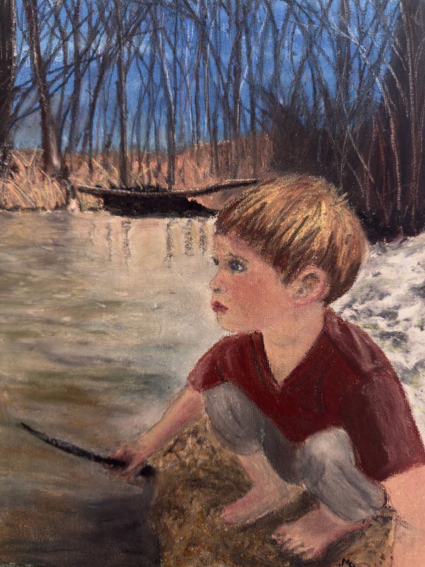 A boy crouches by a river, holding a stick, surrounded by nature.
