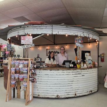 Two women stand behind a rustic round counter in a store.