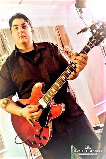 Man playing red electric guitar indoors.