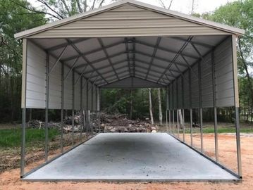 Large metal carport with concrete floor in outdoor setting.