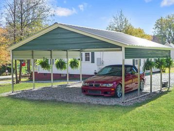 Carport with a red car and hanging plants.