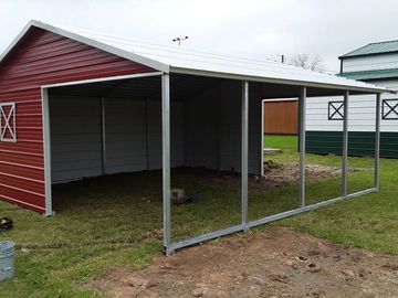 Partially constructed red metal carport with white roof.