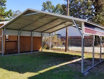 Metal carport structure with a shed in the background on a grassy lawn.