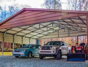 Metal carport with two cars and a tractor inside.