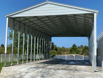 Large metal carport structure under clear blue sky.