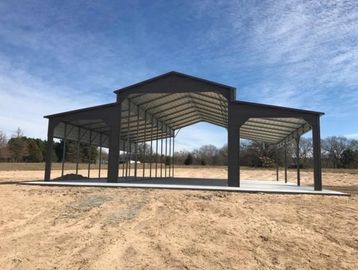 Large open metal structure in a barren field under a blue sky.