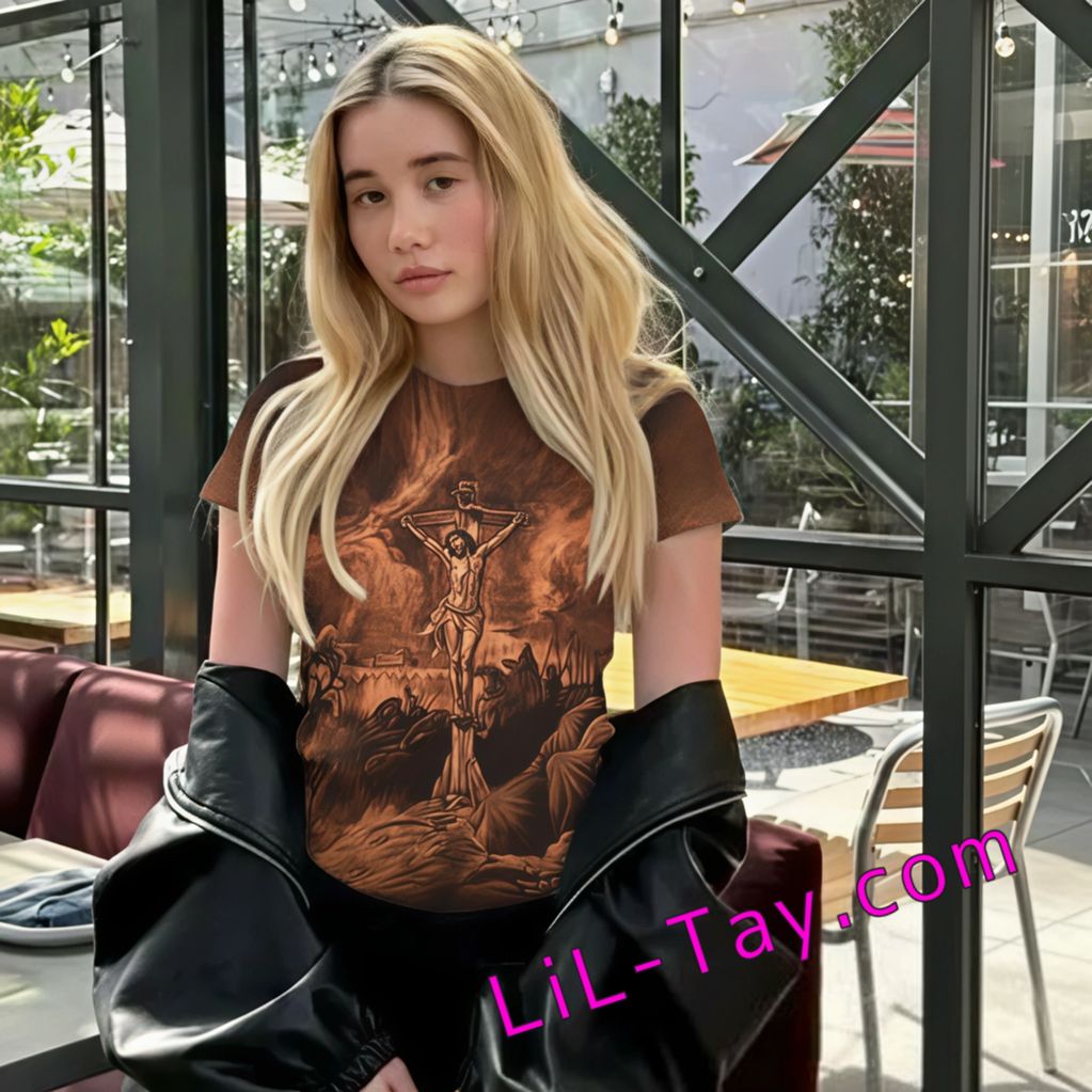 LiLTay with a tee shirt of Jesus on the cross standing in a coffee shop with a black coat around wai