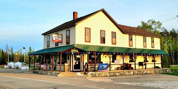 A rustic two-story grocery store with a green roof and porch.