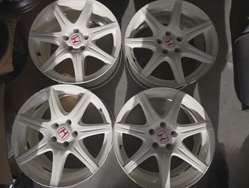 Set of four white Honda alloy wheels with red logos.