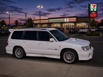 White SUV parked near a 7-Eleven store at dusk.