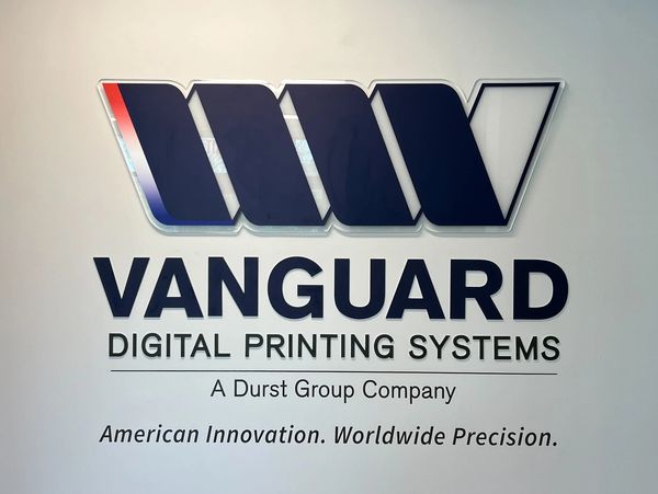 Vanguard Digital Printing Systems logo on a white office wall.