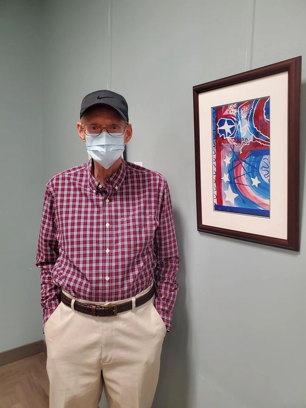 Member poses next to his painting hung in Dine-In Gallery at ARC, Normal, IL